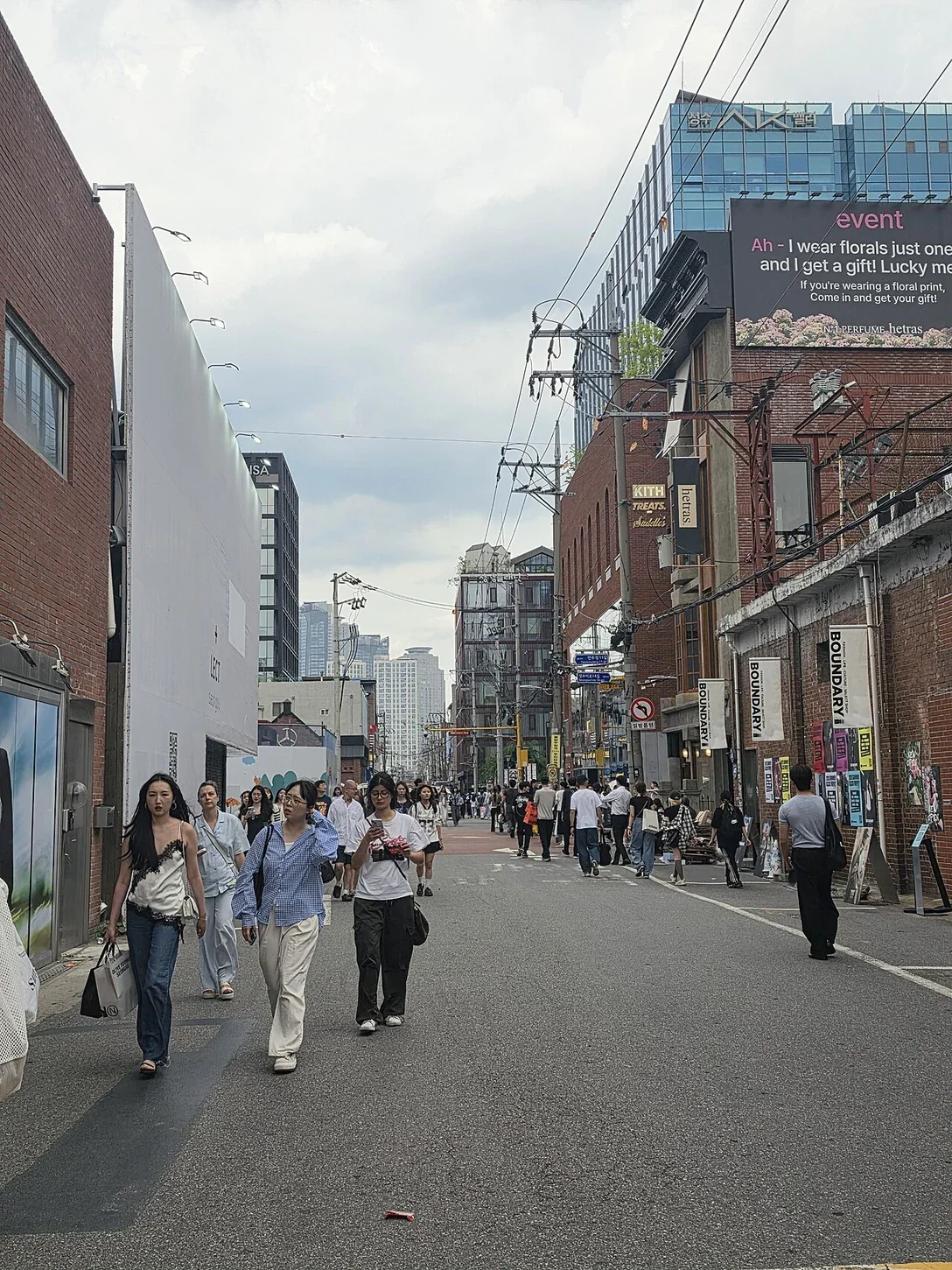 벽돌 건물과 상점 사이를 걷는 사람들이 있는 성수동 거리